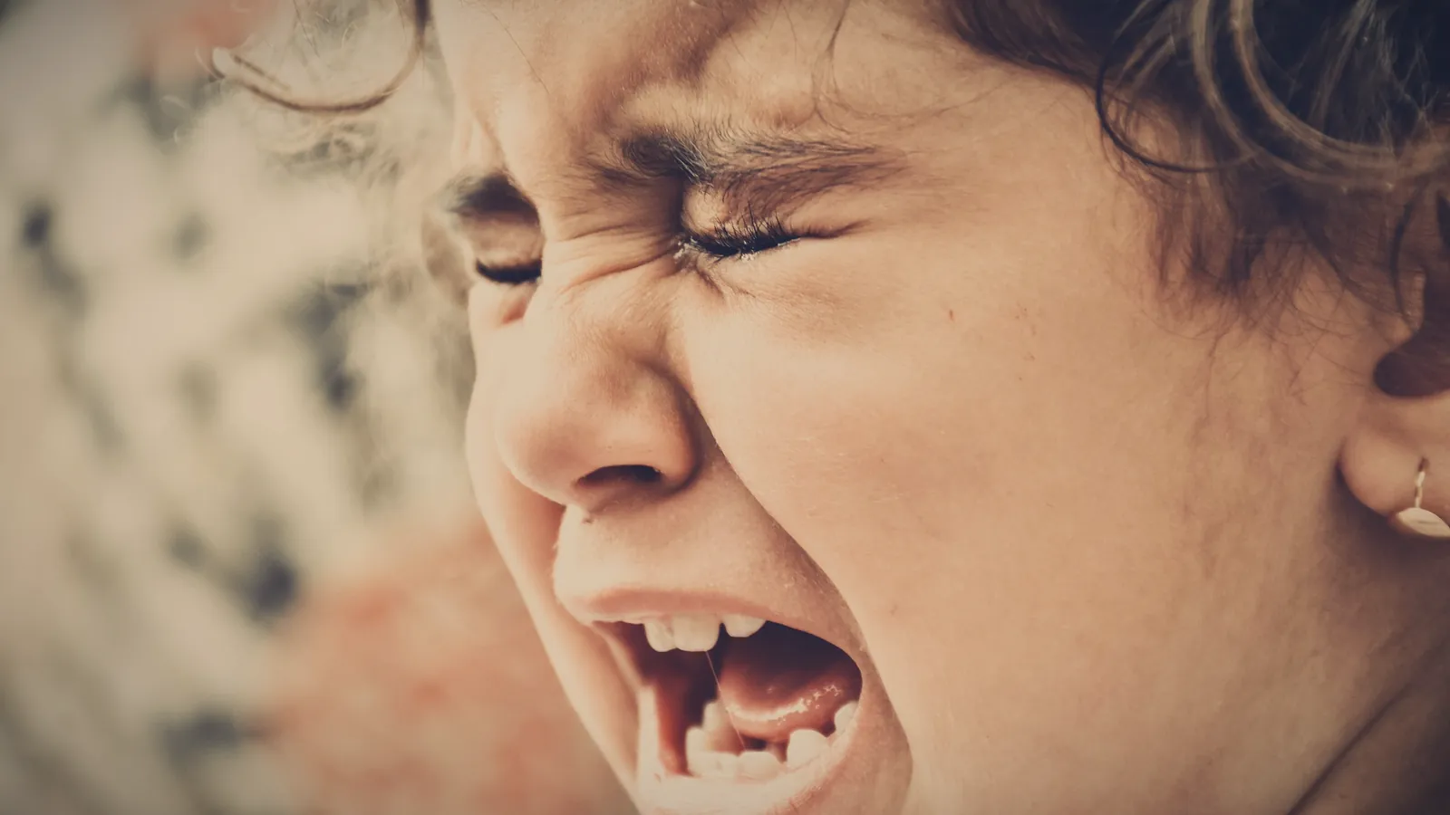 A young girl screaming and crying, eyes squeezed shut, in the middle of a meltdown