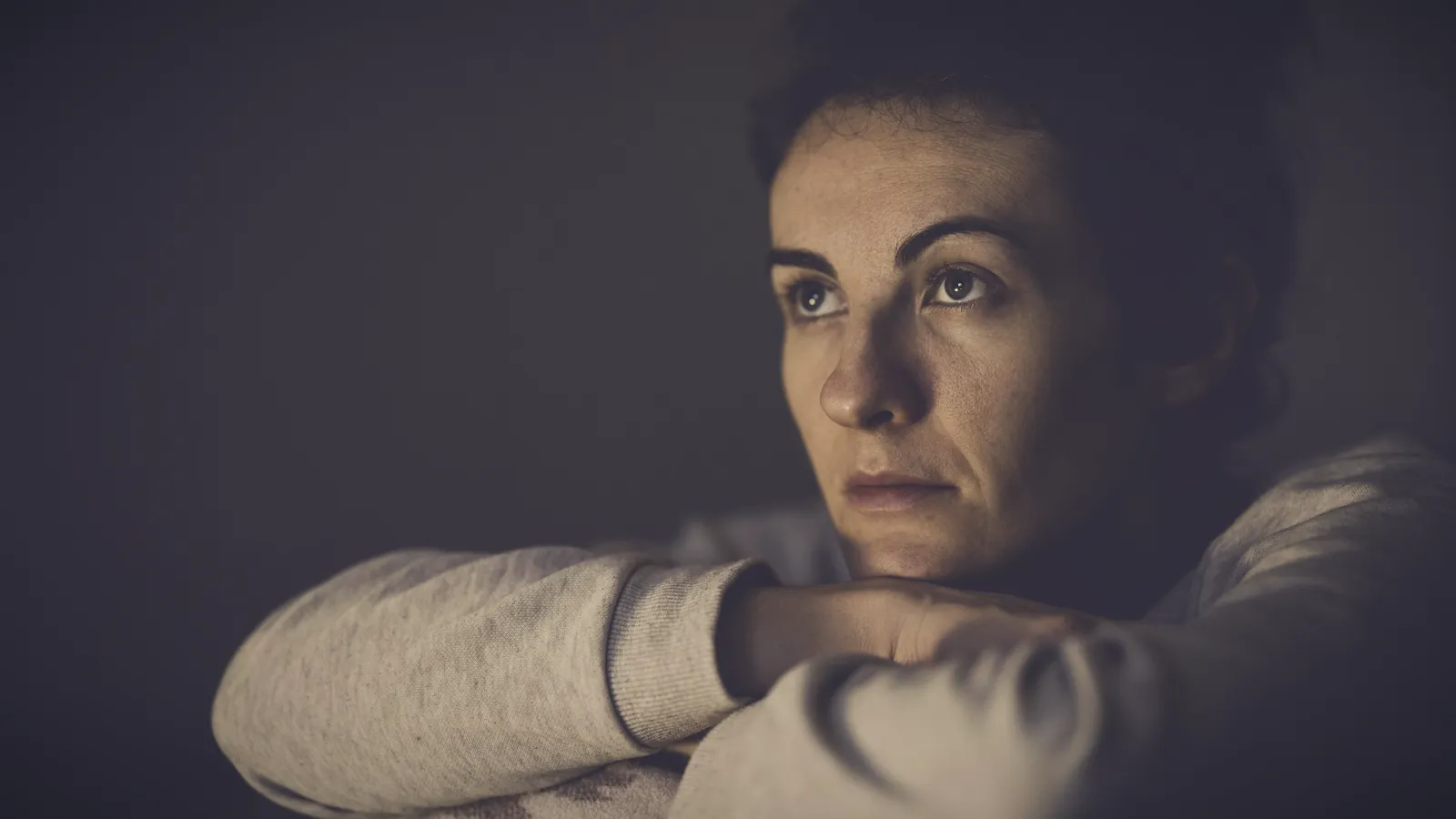 A worried mother resting her chin on her arms, lost in thought